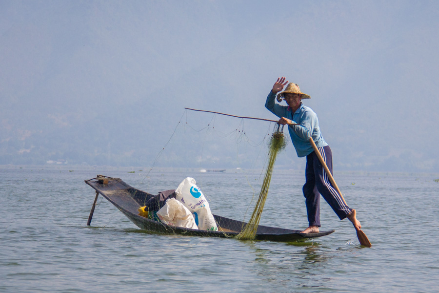Fisherman posing while putting out a net onInle Lake, Myanmar